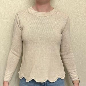 Neutral cream sweater with scalloped bottom edge.